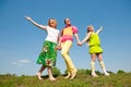 Mother and two daughter jumping on green meadow Royalty Free Stock Photo