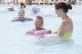 A mother and two daughters are swimming in a public pool