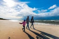 Mother with daughters walking on the seaside beach on a sunny windy day - a family walk by the sea Royalty Free Stock Photo