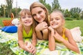 Mother and two girls lying on grass on a picnic and fun look into the frame Royalty Free Stock Photo