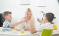 Mother and two kids playing card game at dining table at bright modern home. Royalty Free Stock Photo