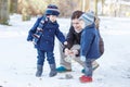 Mother and two little siblings boys feeding ducks in winter. Royalty Free Stock Photo