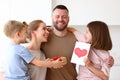 Mother and two smiling kids congratulating dad with Fathers day while standing in kitchen in morning Royalty Free Stock Photo