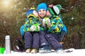 Mother and two sons drink hot tea in a snowy forest after sledging. Family Winter fun for Christmas vacation. Royalty Free Stock Photo