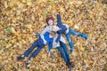 Mother and two sons lying on autumn foliage in forest. Young family in Park. Top view Royalty Free Stock Photo