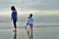Mother and two young children walking playing on the beach photo taken from behind no recognizable people