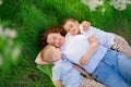 a mother with two young sons lies under the branches of a flowering tree. picnic