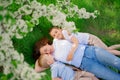 a mother with two young sons lies under the branches of a flowering tree. picnic