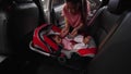 mother unbuckle safety belt and takes the baby out of car seat