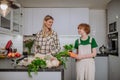 Mother unpacking local food in zero waste packaging from bag with help of daughter in kitchen at home.