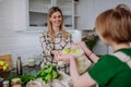 Mother unpacking local food in zero waste packaging from bag with help of daughter in kitchen at home.