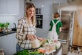 Mother unpacking local food in zero waste packaging from bag in kitchen at home.