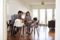 Mother Uses Laptop Whilst Father Plays With Children At Home Royalty Free Stock Photo