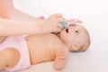 Mother using baby nasal aspirator. She is doing a mucus suction to four months baby girl Royalty Free Stock Photo