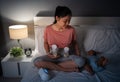 mother using breast pump machine to pumping milk while talking with her newborn baby on bed at night Royalty Free Stock Photo