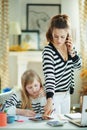 Mother using mobile phone and working and helping child Royalty Free Stock Photo