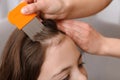 Mother using nit comb on her daughter`s hair. Anti lice treatment