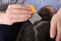 Mother using nit comb on her daughter`s hair indoors. Anti lice treatment