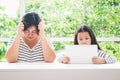 The mother is very stressed. The little daughter is watching the media on the tablet.