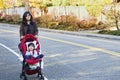 Mother walking with disabled son in stroller o