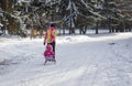 Mother walking on an empty, snowy street driving sledge with kid in Dnepr, Ukraine at December, 04 2016