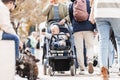 Mother walking and pushing his infant baby boy child in stroller in crowd of people wisiting sunday flea market in