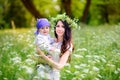 mother walks with kids in the beautiful park on a sunset, strong embraces and holds on hands. Mother on the head has a wreath from