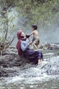 Mother was showering for a baby daughter. At a stream in a rural area of Thailand