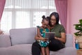 Mother was teaching the daughter through tablet joyfully while sitting on the sofa. black people or African Americans. Home study Royalty Free Stock Photo