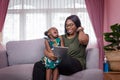 Mother was teaching the daughter through tablet joyfully while sitting on the sofa. black people or African Americans. Home study