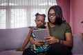 Mother was teaching the daughter through tablet joyfully while sitting on the sofa. black people or African Americans. Home study Royalty Free Stock Photo