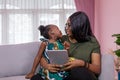 Mother was teaching the daughter through tablet joyfully while sitting on the sofa. black people or African Americans. Home study Royalty Free Stock Photo