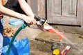 Mother washing childs toys using a water hose, outdoors lifestyle scene. Cleaning children`s toys with water outside, summer