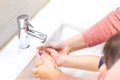 Mother washing her kid& x27;s hand with soap under running tap water Royalty Free Stock Photo