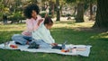 Mother watching daughter tablet playing on picnic. African woman admiring girl Royalty Free Stock Photo