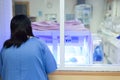 Mother watching at the Newborn baby with hyperbilirubinemia / Neonatal jaundice under blue UV light for phototheraphy on infant