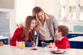 Mother Wearing Business Suit Having Breakfast With Children In School Uniform Before Work Royalty Free Stock Photo