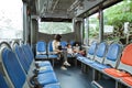 a mother wearing a mask and her two young daughters sit in the back seat of the bus