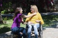 Mother in a wheelchair and her daughter holding their hands and smiling Royalty Free Stock Photo