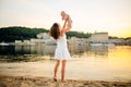 Mother which turns the child against a sunset and water. Happy mom and baby. Playing on beach. Young woman tossing up her son Royalty Free Stock Photo