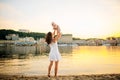 Mother which turns the child against a sunset and water. Happy mom and baby. Playing on beach. Young woman tossing up her son Royalty Free Stock Photo