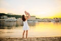 Mother which turns the child against a sunset and water. Happy mom and baby. Playing on beach. Young woman tossing up her son Royalty Free Stock Photo