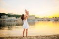 Mother which turns the child against a sunset and water. Happy mom and baby. Playing on beach. Young woman tossing up her son Royalty Free Stock Photo