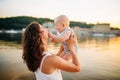 Mother which turns the child against a sunset and water. Happy mom and baby. Playing on beach. Young woman tossing up her son Royalty Free Stock Photo