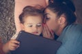 Mother whispered to her daughter on ear and using iPod. Royalty Free Stock Photo