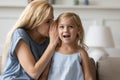 Mother whispers on ear to preschool daughter a secrets Royalty Free Stock Photo