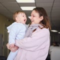 A mother woman holds a happy toddler baby boy in her arms in the lob Royalty Free Stock Photo