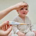 A mother woman measures the temperature of a sick toddler baby wit Royalty Free Stock Photo