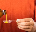 Mother woman pouring liquid medication or antipyretic syrup cough from bottle to spoon