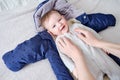 A mother woman puts on warm clothes for a baby boy. Mom dresses a happy child in winter clothes on the bed Royalty Free Stock Photo